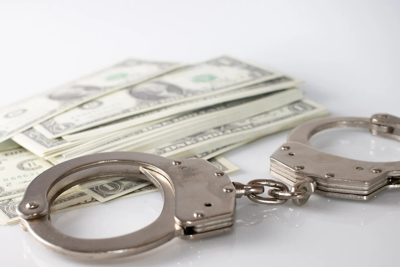 Handcuffs next to a stack of money.
