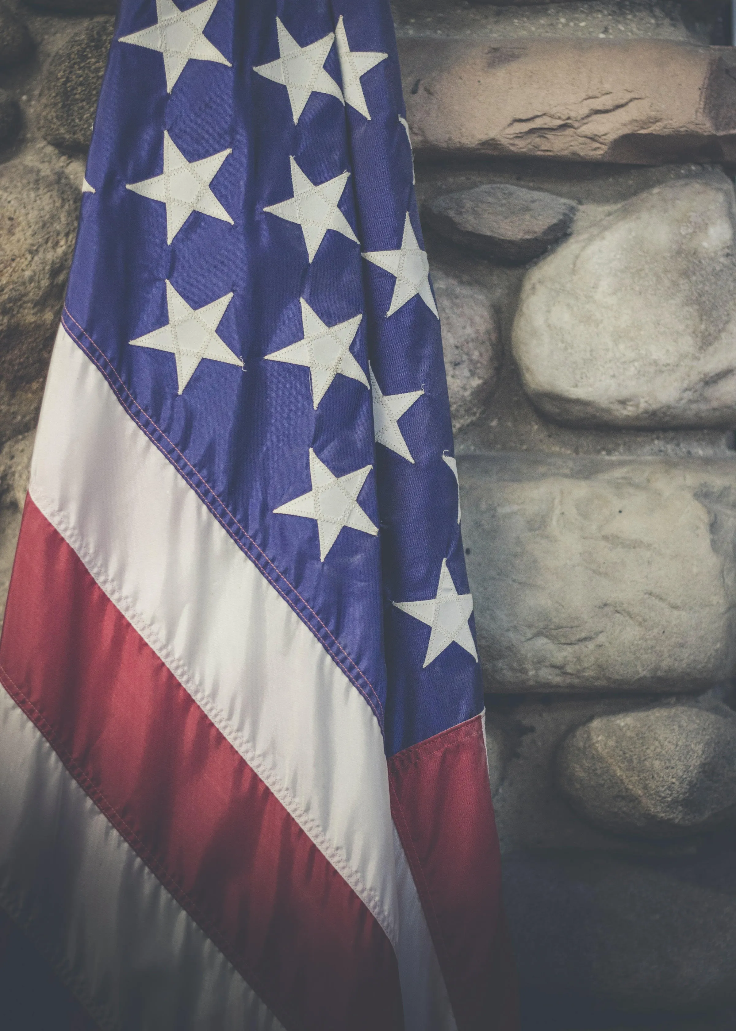 American flag in front of stone wall
